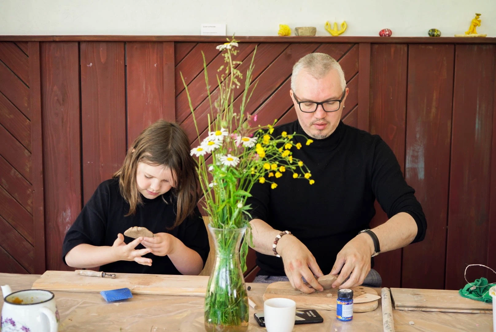 An adult and a child making objects from clay