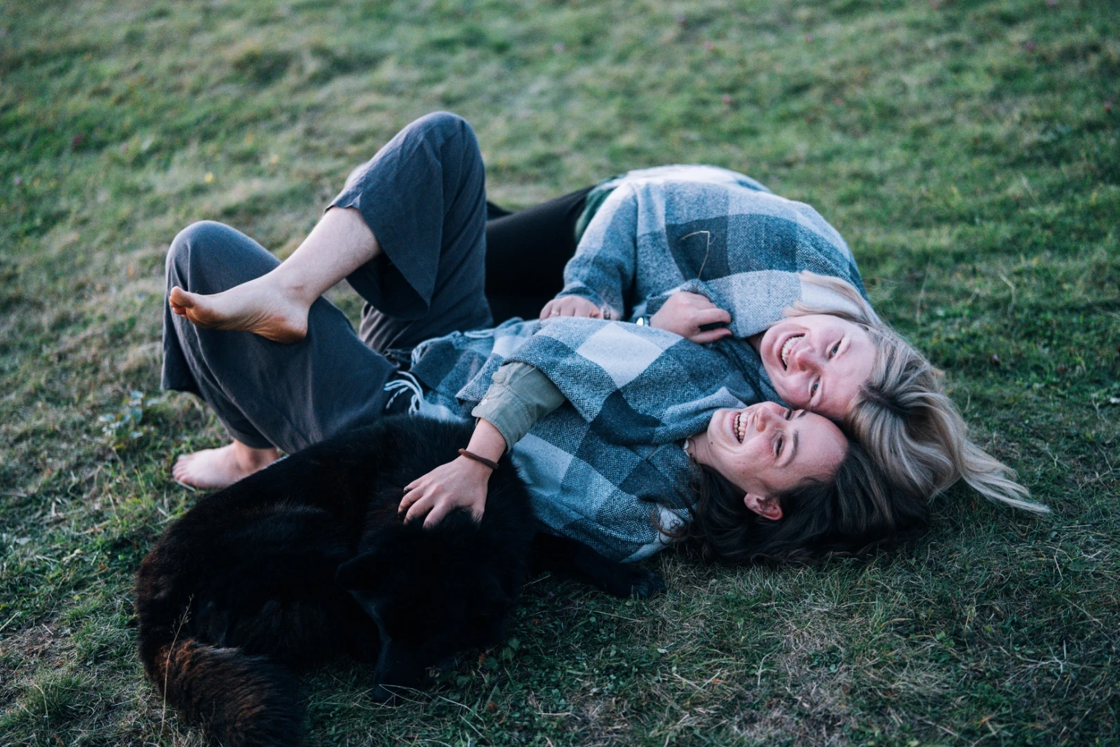 Two people resting on grass beside a dog