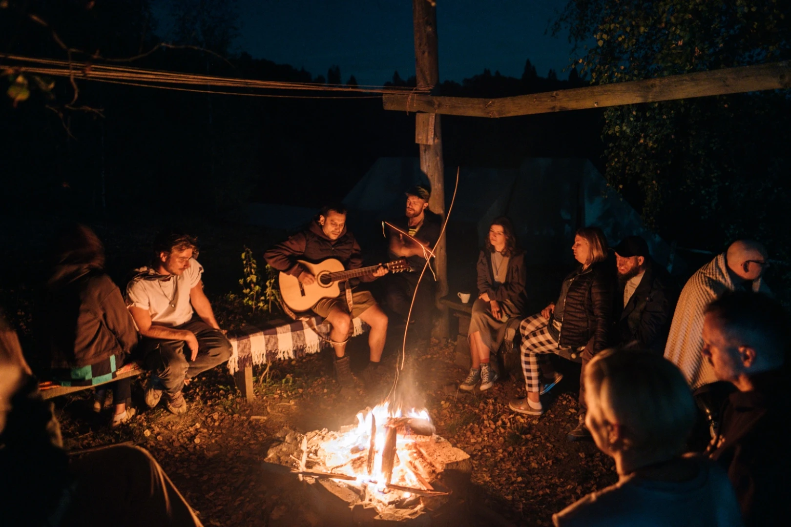 People gathered around a campfire with a guitar