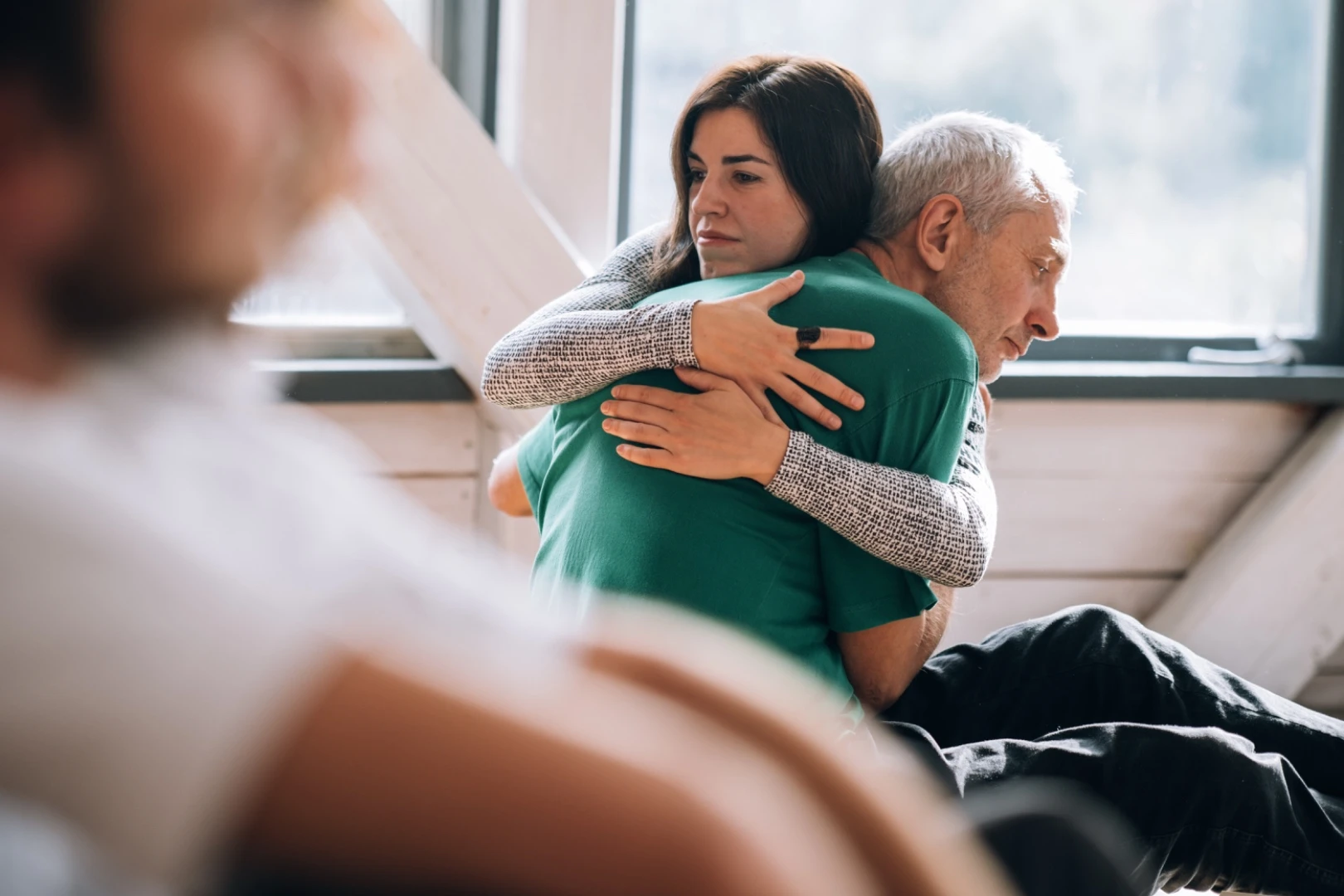 Two participants embracing by a window